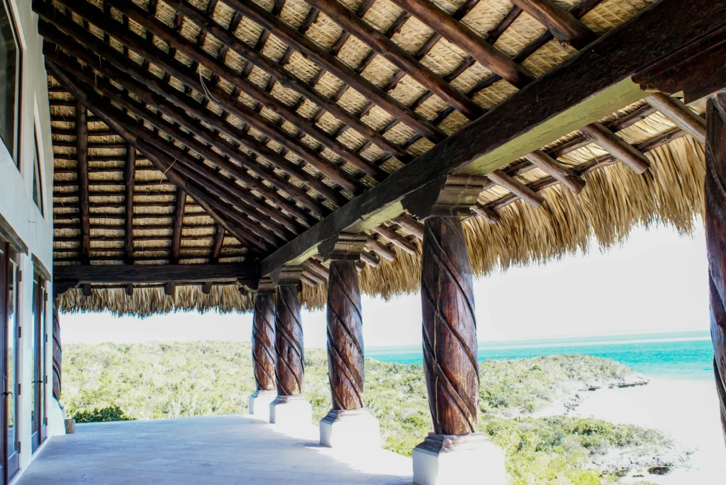 Thatch roof structure with wooden columns overlooking a coastal view, enhancing beach property aesthetics and functionality.