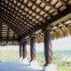 Tiki hut pavilion showcasing natural thatch roofing and decorative wooden columns, emphasizing outdoor design aesthetics and landscaping for resorts and beach properties.